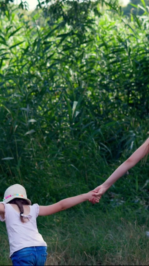 A woman plays with her daughters while cleaning up trash on a riverbank Stock Footage 340576814