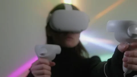 Woman plays video game while wearing VR headsetmoving joysticks in cyberspace Stock Footage 242275137