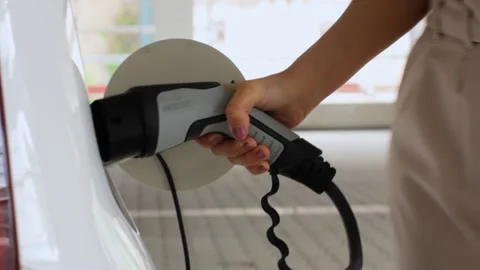 Woman plugging a power supply cable to an electric car. Zero emission vehicle Stock Footage 133010479