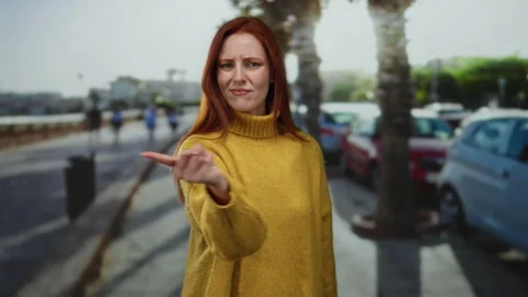Woman pointing with an assertive expression on a city street wearing a yell.. 스톡 동영상 312005229