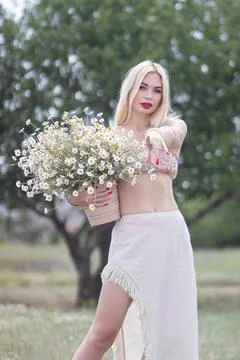 Woman pointing at camera while holding pot of daisies Stockfoto's