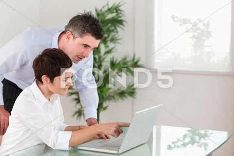 Woman pointing at something to his colleague on a notebook Stock Photos