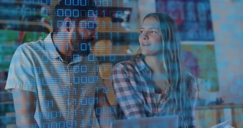 Woman pointing tablet, guiding developer to laptop while floating binary digits Stock Footage 317841641