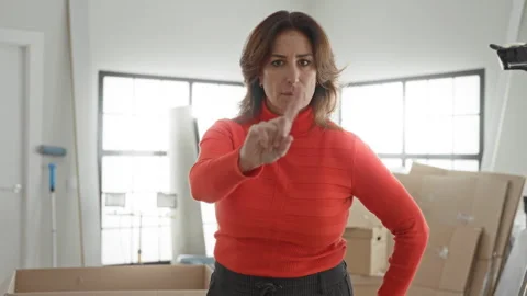 Woman points finger at camera amid moving cardboard boxes in building weari.. Stock Footage 337441879