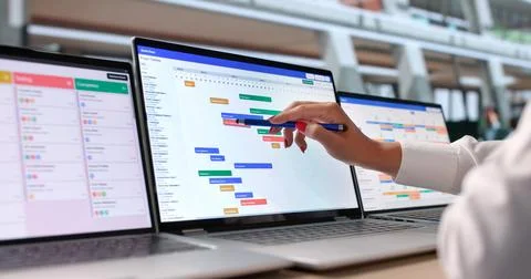 Woman Points At Laptop Screen While Checking Teams Project Timeline. Stock Photos
