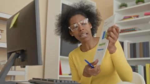 Woman points pen at document with hand beside computer monitor in office bu.. Stock Footage 337377978