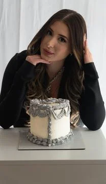 A woman is posing with a cake on a table Foto stock