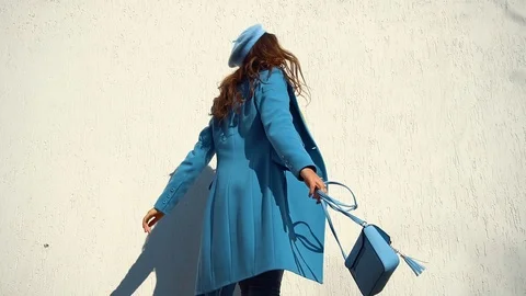 Woman posing in a coat on the background of the wall with the handbag Video stock 104866116
