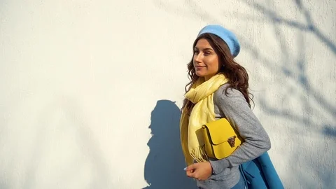 Woman posing in a coat on the background of the wall with the handbag Stock Footage 104866274