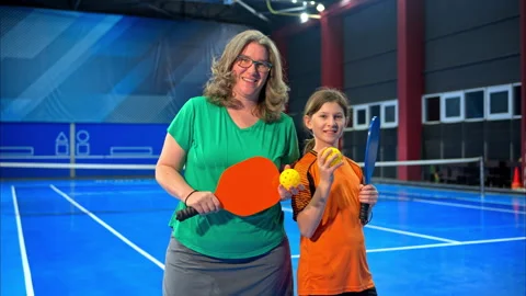 A woman posing with her daughter after playing pickleball on a blue, inside Stock Footage 297497953