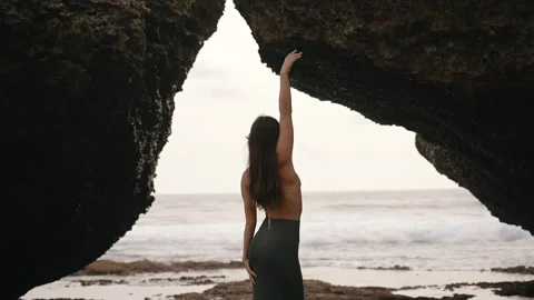 Woman posing with ocean view through rocky arch Stock Footage 303394389
