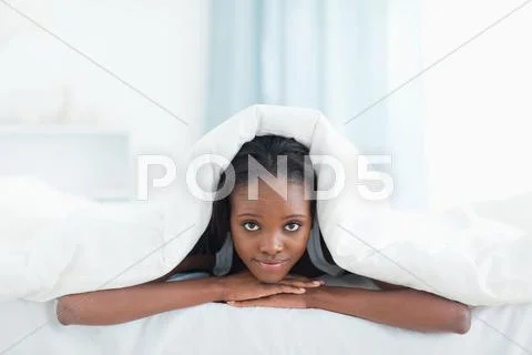 Woman posing under a duvet Stock Photos