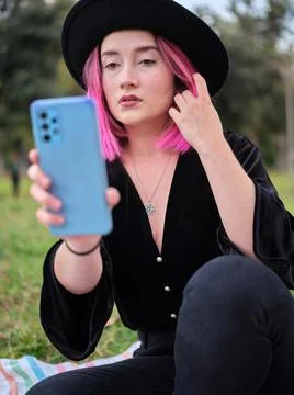 Woman posing while looking at her mobile phone and touching her pink hair Stock Photos