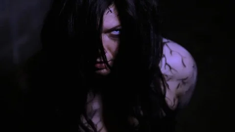 A woman possessed by a demon looks up threateningly at the camera. Stock Footage