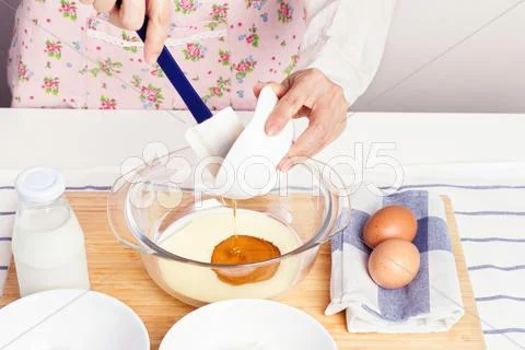 Woman Pouring Honey Into Milk For Mixing Baking Ingredients For Healthy Muffi