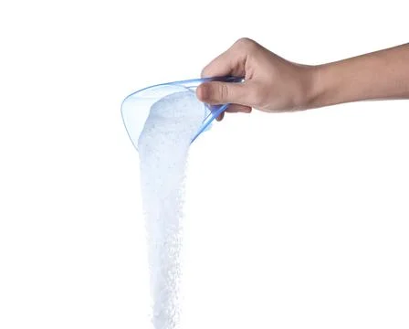 Laundry detergent in plastic measuring cup and towels on white