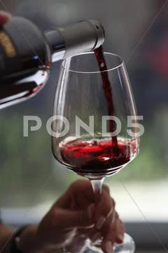 A woman pouring a sampling of red wine at a wine tasting, focus on hands Stock Photos