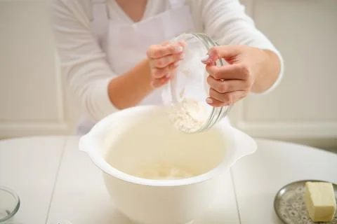 A woman pours flour into a bowl for making pie dough. Process of cooking peca Stock Photos