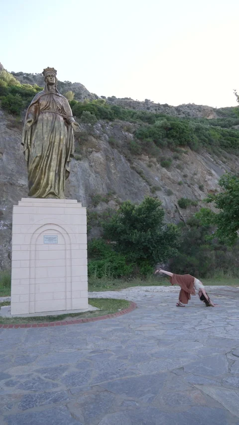 Woman practicing advanced yoga flow near Virgin Mary statue in Sirince Stock Footage 336164512