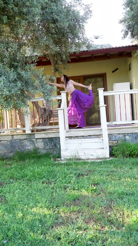 Woman practicing dancer yoga pose on a rustic cottage porch Stock Footage 336148099
