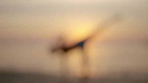 Woman practicing half moon pose on the beach during sunset Stock Footage 75287497