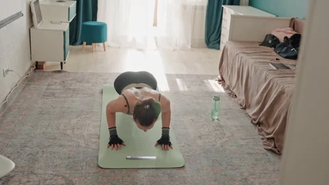 Woman practicing pushups on carpet. Indoor fitness environment where woman Stock Footage 342425170
