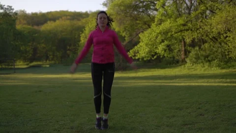 Woman Practicing Warm-Up Exercise Jumping Early in the Morning in the Spring Stock Footage 75320763