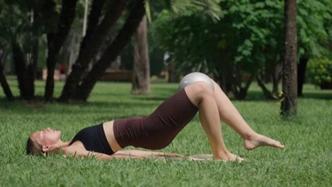 Woman practicing yoga bridge exercise outdoors in a park 库存影片 284926232