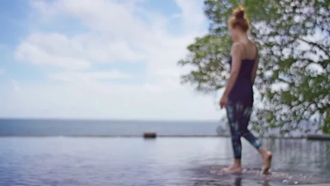 Woman practicing yoga in infinity pool against sea Stock Footage 74774393