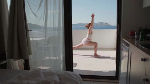 Woman Practicing Yoga Warrior Pose on Terrace with Sea View Video stock 346072985