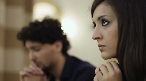 Woman in prayer in a church , desperate man in background Stock Footage