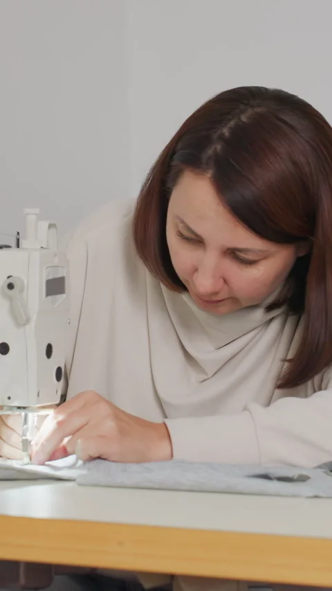 Woman precisely guiding thread through sewing machine with focus, Calm female Stock Footage 323807028