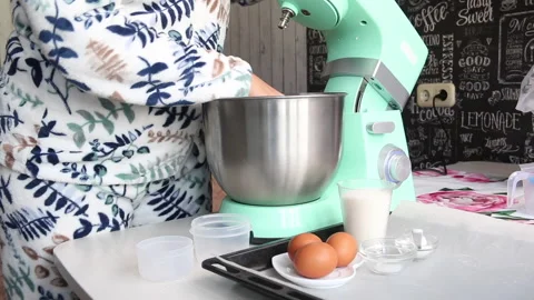 A woman prepares a planetary mixer for work. On the table are the ingredients Stock Footage 210793357