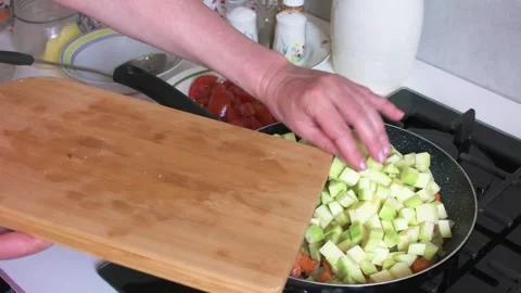 A woman prepares zucchini caviar by adding chopped zucchini to fried onions.. Video stock 346148786