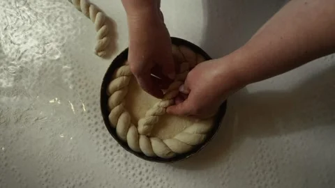 Woman preparing braided bread dough in a round baking pan, hands skillfully Vídeo Stock 332736884