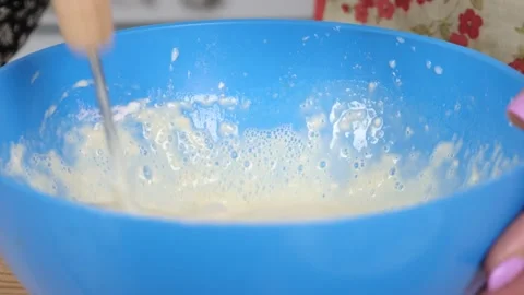 Woman preparing dough, adding milk and stirring with a whisk Stock Footage 239945623