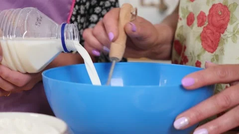Woman preparing dough, adding milk and stirring with a whisk Stock Footage 239945627