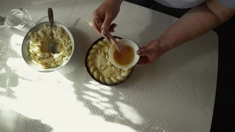 Woman preparing dough in a kitchen, applying egg wash with a brush onto braided Vídeo Stock 332736894