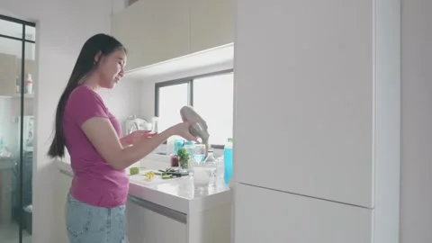 A woman is preparing a drink in a kitchen Stock Footage 313942916