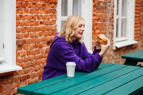 Woman is preparing to eat appetizing burger in the street cafe, fast food Stock Photos