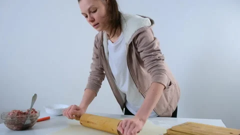 Woman is preparing to roll dough for dumpings using rolling pin on table. Video stock 153889448