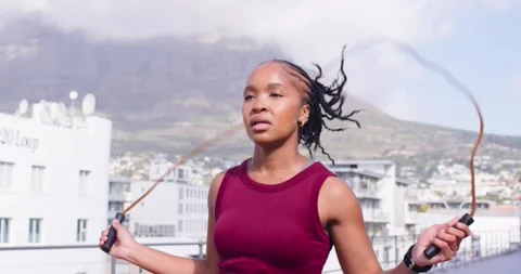 Woman preparing rope, jumping on rooftop for workout, wearing maroon tank, Vidéo 340674811