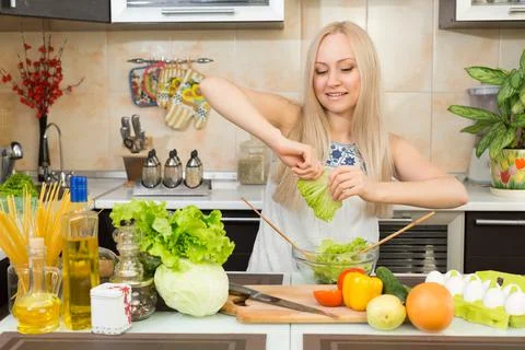 Woman preparing salad at the kitchen table Stock Photos