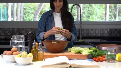 Woman preparing a salad while reading a recipe Video stock 254286485