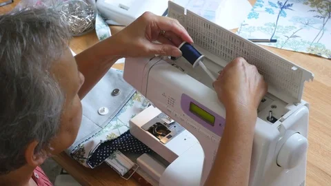 Woman preparing sewing machine for use in her studio. She is preparing to make a Video stock 77256858