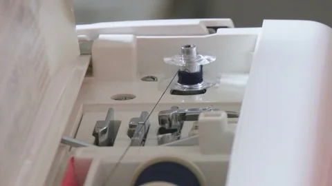 Woman preparing sewing machine for use in her studio. She is preparing to make a Stock Footage 77258477