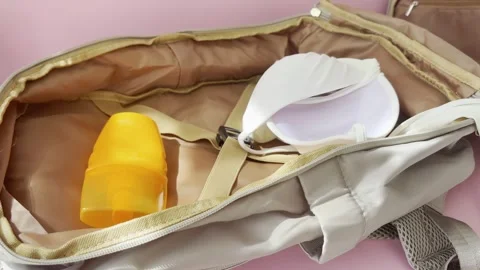 Woman preparing a summer backpack with sunscreen, sunglasses, and a swimsui.. Stock Footage 334617385