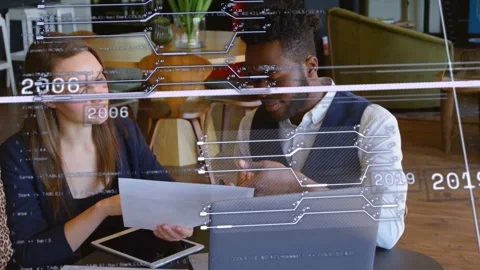 Woman presenting chart to man, both consulting devices as AR timeline guiding Stock Footage 333803459
