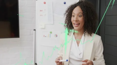 Woman presenting holding marker while finance graphs appearing over board, Stock Footage 333368394
