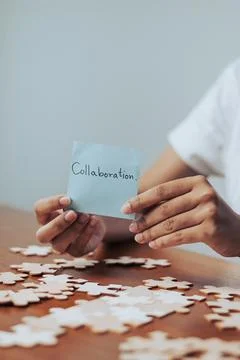 Woman presenting a note about teamwork surrounded by colorful puzzle pieces.. Stock Photos